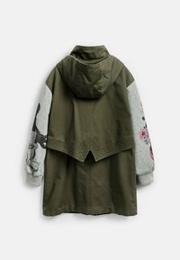 Olivgrön jacka med huva, grå ärmar med blommiga och grafiska mönster. Texturerad bakre fåll med spetsig skärning.