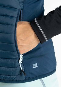 Navy Softshell-Jacke mit einer Reißverschlusstasche und schwarzer Innenausstattung mit kontrastierenden Nähten; enthält ein sichtbares Markenlogo "ILUS."