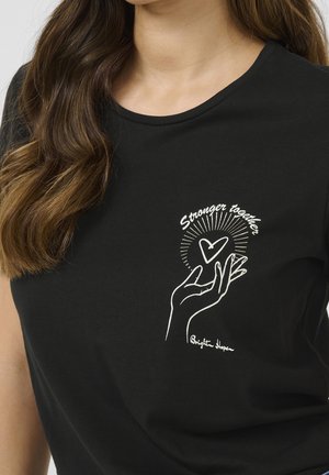 T-shirt noir avec un dessin en ligne blanche d'une main tenant un cœur, des rayons autour, avec le texte "Plus forts ensemble" au-dessus et "Brighton Hope" en dessous.