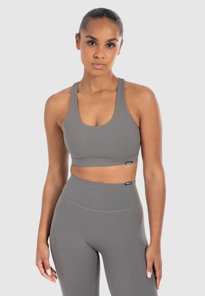 Grijze sportbeha met een ronde hals en brede banden, gecombineerd met bijpassende high-waisted legging; gladde textuur, minimale branding.