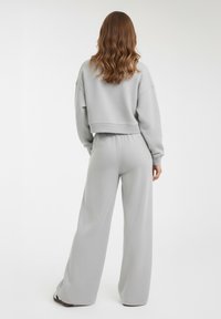 Completo da casa grigio chiaro in due pezzi composto da una felpa corta e pantaloni a gamba larga con tessuto texturizzato e vita elastica.