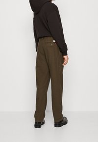 Bruine geruite broek met een relaxte pasvorm, voorzien van een achterzak en een tailleband. Gekocht met een zwarte hoodie.