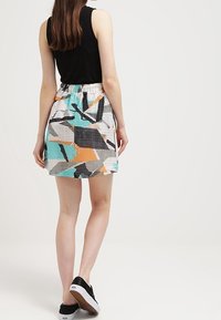 Jupe colorée avec un motif géométrique en turquoise, orange, noir et gris, dotée d'une taille élastique et d'un tissu léger.