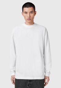 Weißes Langarmshirt mit Rundhalsausschnitt, aus einem glatten Baumwoll-Mix gefertigt. Mit überschnittenen Schultern und lockerer Passform.