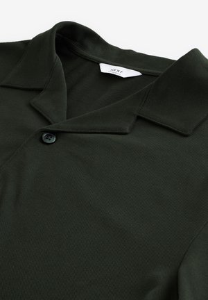 Polo shirt verde scuro realizzato in tessuto testurizzato, con colletto a punta e chiusura con un solo bottone. Etichetta del marchio visibile all'interno del colletto.