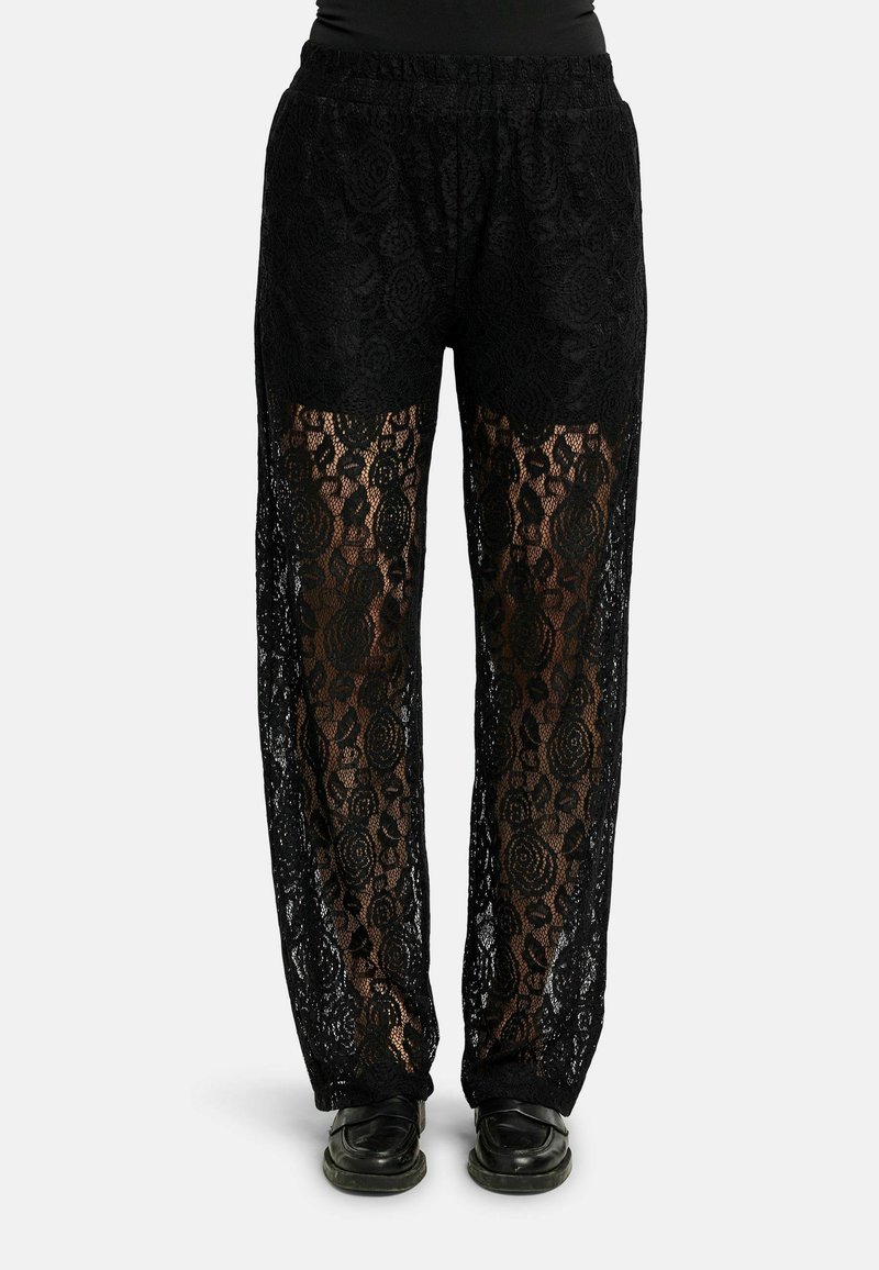 Juodos nėrinės kelnės su elastinga juosmens juosta, puoštos gėlių raštais ir permatomais intarpais, derinamos su juoda avalyne.