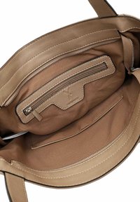 Interieur van een tan leren handtas met een ritszak en een zacht stoffen voering. Soepele textuur met contrasterende stiksels.