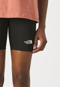 Mustad mustad spordilühendid, millel on sobiv disain, esiküljel asuv väike valge "The North Face" logo madalamal vasakul jalal. Sile tekstuur.