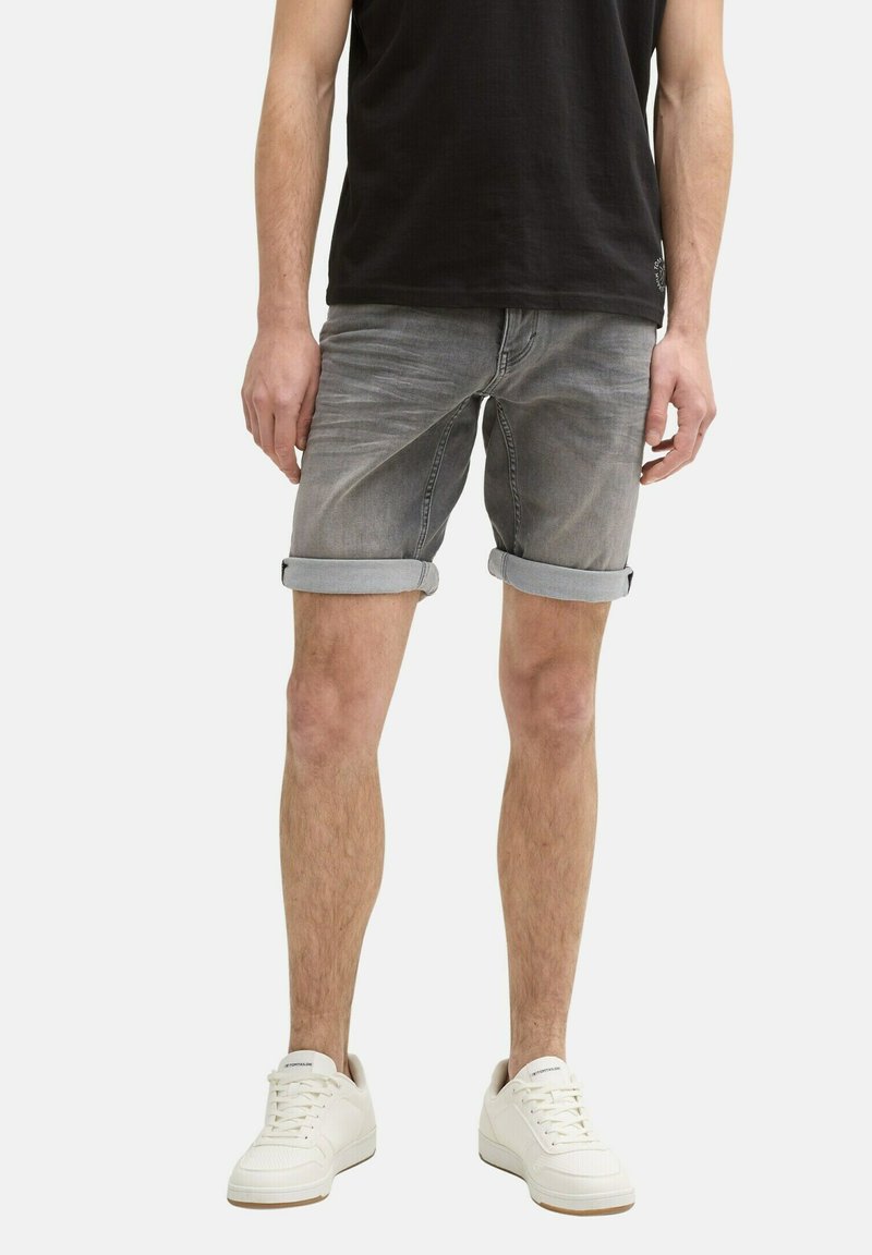 Grijze denimshorts met opgerolde manchetten, vervaagd uiterlijk, vijf-pocket ontwerp, gecombineerd met witte sneakers en een zwart T-shirt.