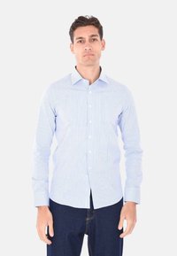 Camicia a maniche lunghe a righe in azzurro chiaro e bianco, con colletto button-down, bottoni frontali e un design aderente.