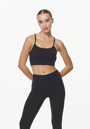Black sports bra with thin straps paired with high-waisted black leggings. Smooth fabric, fitted design, ideal for athletic activities.