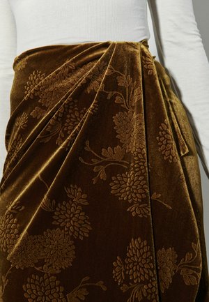 Braoter Samtrock mit Blumenmuster, der mit einer drapierten Form und weicher Textur versehen ist. Kombiniert mit einem weißen gerippten Oberteil.