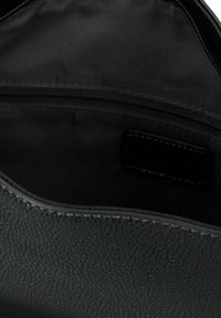 Zwarte, gestructureerde leren handtas interieur, met een ritsvak en een gladde stofvoering. Gestikte randen zichtbaar.