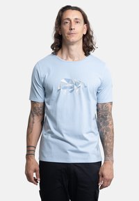 Camiseta de algodón en un azul claro con un diseño geométrico de un oso en azul y blanco. Mangas cortas, escote redondo y un ajuste relajado.