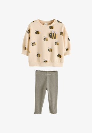 Beebimustriga beež pikkade varrukatega pealis, millel on 3D mesilase detail, ja must-valgete triibuliste retuusidega, millel on volangiga ääred. Väikelapse komplekt.