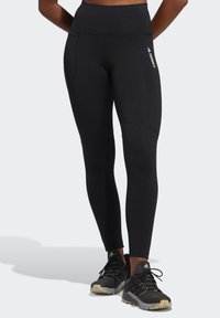 Sorte træningsleggings med høj talje, sidelommer og en glat tekstur. Har elegante linjer og mærkeaccenter på siden.