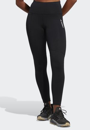 Fekete fitnesz leggings, magas derékpánttal, oldalsó zsebekkel és sima textúrával. Karcsú vonalakkal és márkázott részletekkel az oldalon.