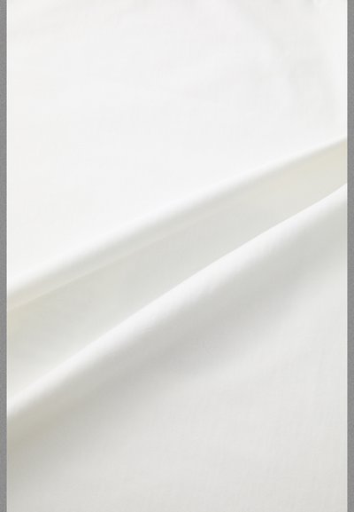 Baltas audinys su lygia tekstūra, turintis subtilias vagas ir raukšles, sukuriantis švelnų, plaukiojantį įvaizdį. Nėra matomų raštų ar priedų.