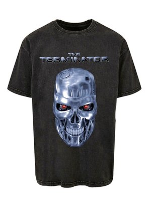 Camiseta de algodón negra con un gráfico de un skull metálico con ojos rojos y el texto "THE TERMINATOR" arriba en plateado. Corte relajado, cuello redondo.