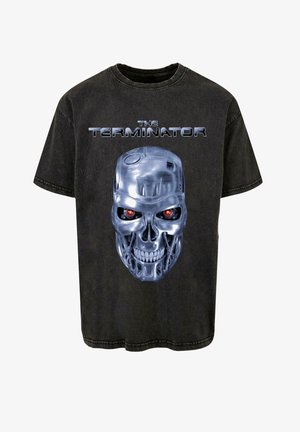 Zwarte katoenen T-shirt met een afbeelding van een metalen schedel met rode ogen en de tekst "THE TERMINATOR" erboven in zilver. Relaxte pasvorm, ronde hals.