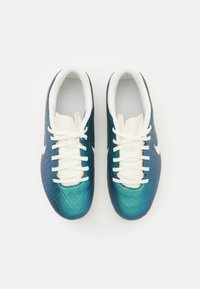 Scarpe da calcio Nike con tomaia imbottita in teal, texture trapuntata, lacci bianchi e fodera interna bianca. Design slim e arrotondato con fori di ventilazione.