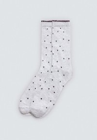 Calcetines de algodón grises con un patrón de lunares en marrón oscuro. Tienen un puño acanalado con bordes en forma de ola, lo que proporciona un detalle texturizado.