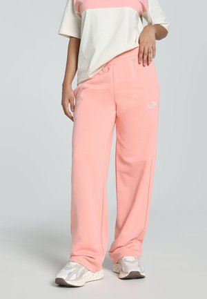 Lichtroze joggingsbroek met een elastische tailleband en subtiele Puma-logo; gecombineerd met een beige en roze shirt met korte mouwen. Zachte, casual uitstraling.