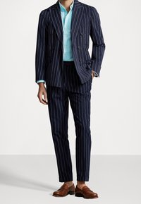Marinblå randig kostym med dubbelknäppt jacka och matchande byxor, tillsammans med en ljusblå skjorta och bruna loafers.