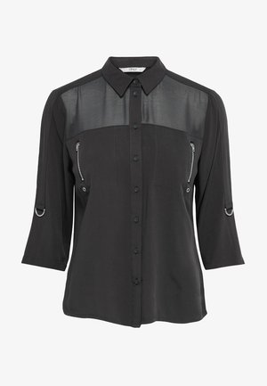Chemise noire à manches longues avec panneau supérieur transparent, boutonnage devant, poches poitrine zippées et détails en anneaux métalliques sur les manches.