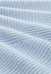 Jasnoniebieska dziana tkanina o teksturowanym, prążkowanym wzorze, z miękkimi włóknami i subtelnymi variacjami odcienia w całej powierzchni.