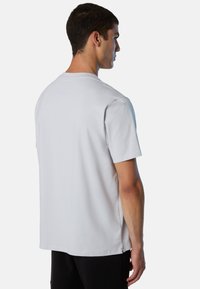 T-shirt grigio chiaro a maniche corte realizzato in tessuto morbido, con colletto a girocollo e taglio dritto, dotato di spacchi laterali all'orlo per facilitare i movimenti.