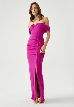 Fuksia off-shoulder mekko, jossa on rypytysdetaili, reisi- korkeudelle ulottuva halkio ja tiukasti istuva siluetti. Valmistettu sileästä, joustavasta materiaalista.