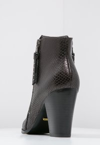 Stivaletti alla caviglia marroni con tacco alto, caratterizzati da un motivo di pelle di serpente testurizzato, zip laterale e tacco a blocco, con una suola nera liscia.