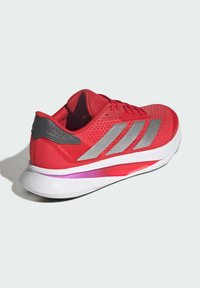 Red running shoe with a mesh upper, grey accents, and three stripes. Features a white and pink sole for cushioning and support.