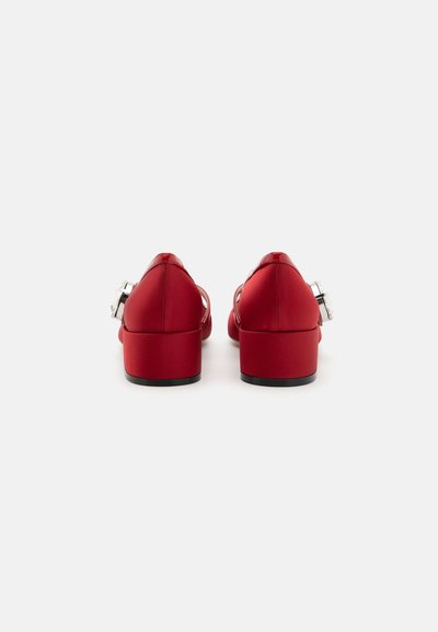 Piros selyem blokkal magasított cipők nyitott hátsó dizájnnal és ezüst színű kiegészítőkkel. Simára kifeszített textúra és lekerekített orrforma.
