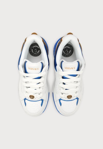 Ζευγάρι λευκά και μπλε Versace sneakers με λευκά κορδόνια, χρυσό έμβλημα Μέδουσα μπροστά και μαύρο λογότυπο Μέδουσα μέσα στην περιοχή της φτέρνας.