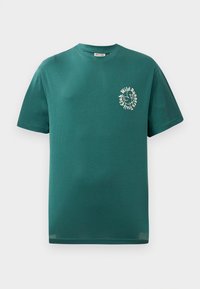 Tirkizna majica kratkih rukava s kontrastnom okruglom ovratniku, na prsima s malim bijelim grafikonom ptice i okruglim tekstom "Wild Runners Trail Club".