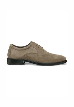Zapato formal de ante marrón con una superficie lisa, puntera redonda y seis ojales. Presenta una suela de goma negra con estrías horizontales.