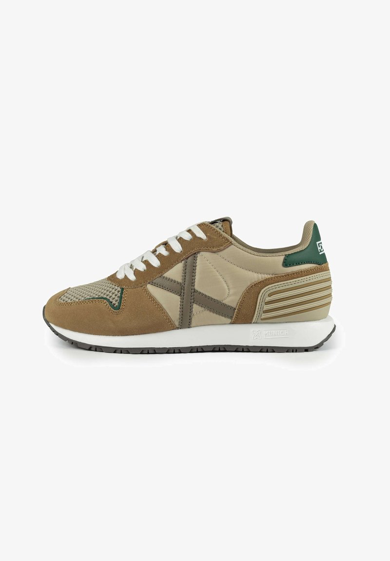 Beige und braune Sportschuhe aus Wildleder und Mesh-Materialien, mit weißen Schnürsenkeln, grünen Akzenten, strukturierten seitlichen Details und Gummisohle.