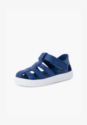 Infradito in gomma blu navy con suola bianca rigata, dotati di design a fascette incrociate e fibbia regolabile sul lato, ideali per comfort e traspirabilità.