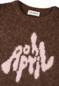 Pruun villane kampsun, mille tekstuur on puudutades pehme ja karvane. Ees on roosa logo, millel on sõnum "Oh April" mängulises ja ebaühtlases fondis.