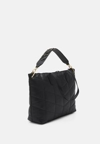 Black quilted handbag with two straps, one studded wide shoulder strap with gold hardware, against a plain white background.