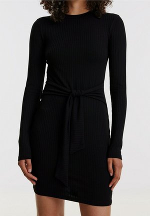 Robe noire à manches longues côtelées avec une taille ceinturée et un détail en nœud, réalisée dans un tissu extensible pour une silhouette ajustée.