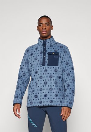 Pull en polaire bleu clair avec un motif géométrique, col zippé à mi-hauteur, poche poitrine navy et accents contrastants navy.