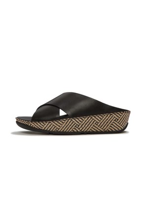 Zwarte leren slip-on sandaal met gekruiste bandjes en een sleehakzool met beige en zwart geometrisch design.