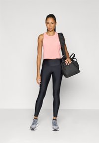 Top de treino cor-de-rosa em rede, leggings pretas de cintura alta, ténis desportivos cinzentos e um saco de desporto preto. Design minimalista, estilo ajustado.