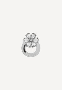 Zilveren bloemvormige ring met heldere, druppelvormige stenen en een ronde band gegraveerd met "GUESS." Gladde, gepolijste oppervlakte.