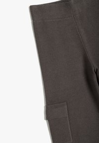 Mørkegrå leggings lavet af tekstureret stof, med en ribbet talje og en sidelomme med stikninger.