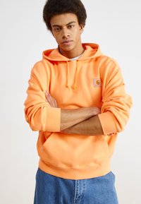 Oranje hoodie van een katoenmix, met een voorste buidelzak, ribgebreide manchetten en een geweven logo etiket op de borst. GStyled met denim shorts.