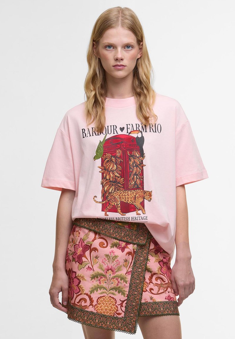 Φωτεινό ροζ oversized t-shirt με γραφικό ενός κόκκινου τηλεφωνικού θαλάμου, μαζί με μια λεοπάρδαλη και τροπικά στοιχεία. Συνδυάζεται με μια κοντή φούστα με λουλουδάτη κέντημα.